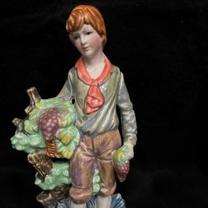 Vintage, porcelain, hand painted figurine of a boy carrying grapes.